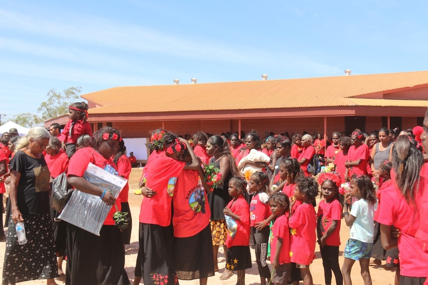 Mourners wearing red embrace.