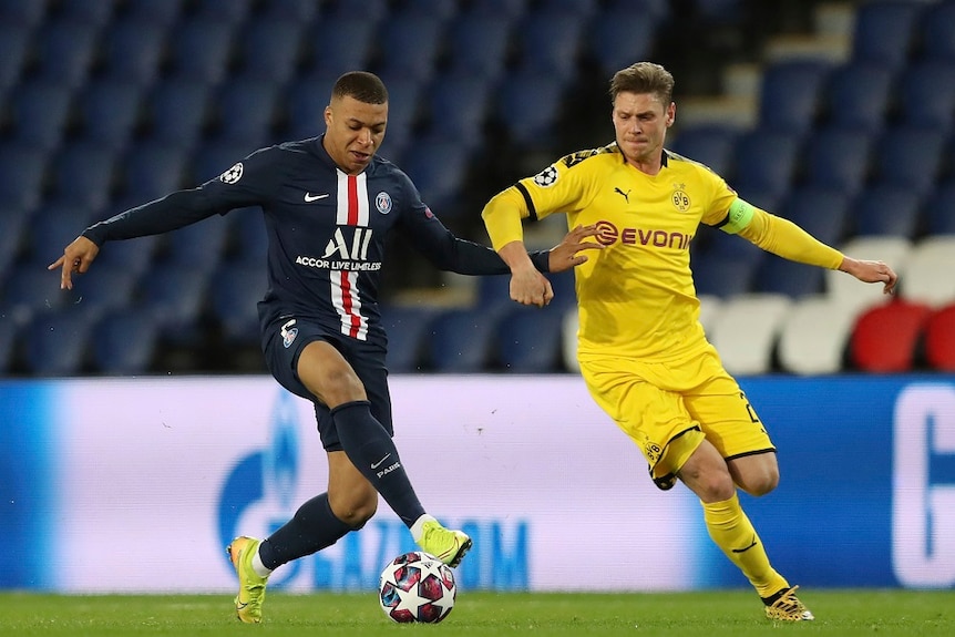 Two soccer player chasing a ball.