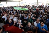 Mourners react over coffins during a funeral ceremony for victims following the suicide bomb attack in the southern Turkish town of Suruc