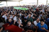 Mourners react over coffins during a funeral ceremony for victims following the suicide bomb attack in the southern Turkish town of Suruc