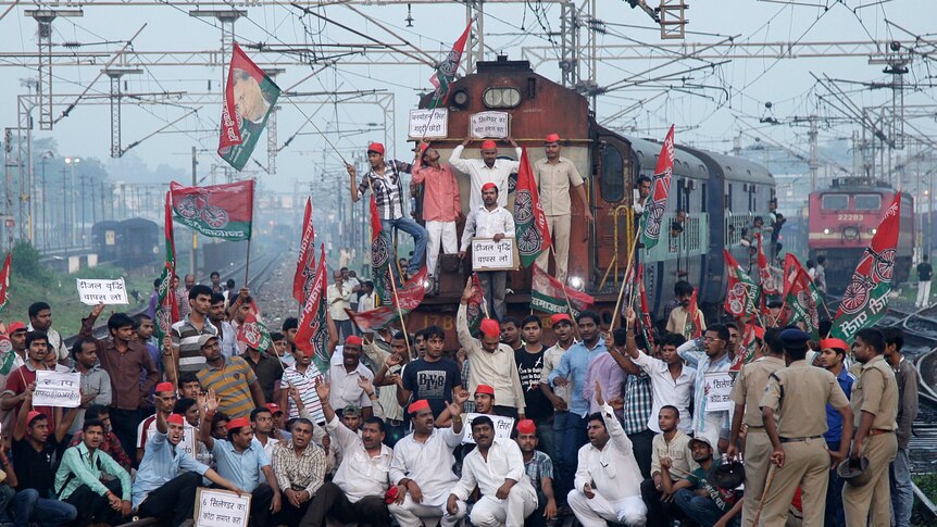Demonstrators from the Samajwadi Party stop a passenger train during a protest