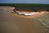 An aerial photograph of remote, ochre-coloured rocky coastline.