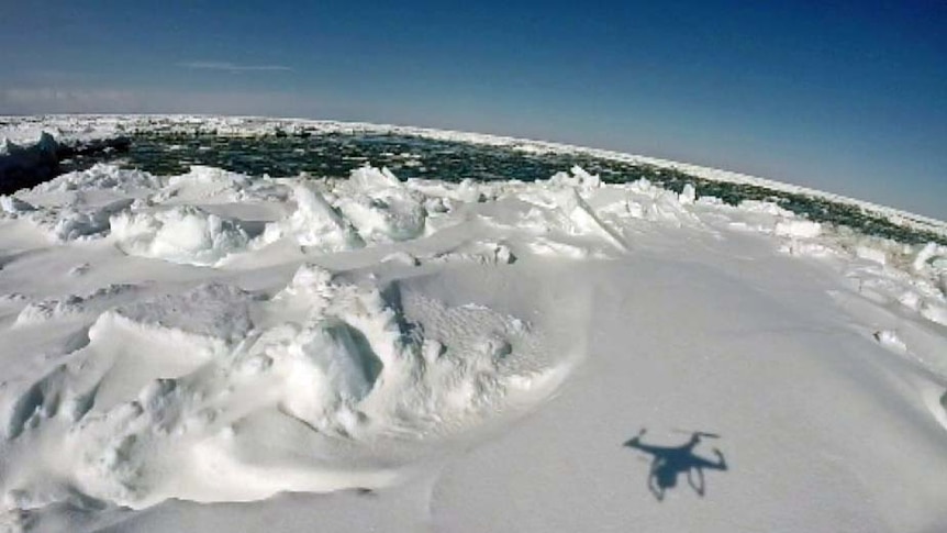 A drone casts a shadow while flying over sea ice in Antarctica.