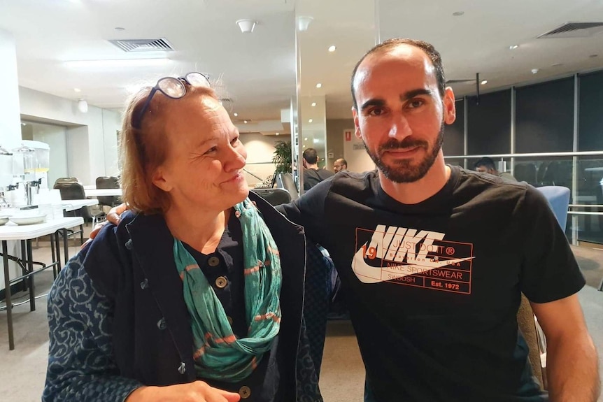 Refugee Moz and Jane Salmon pictured in a hotel meeting room. Mustafa's arm is around Jane's shoulders.