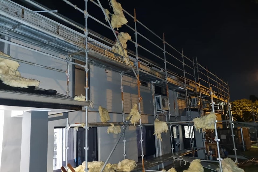 A house with scaffolding around it is badly damaged by a storm.