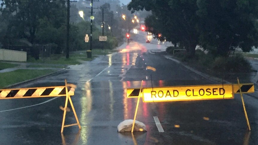 Closed Road sign blocks a flooded street in the light of dawn.