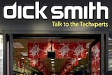 People, blurred by their movement, walk past the front of a Dick Smith store, with the Dick Smith logo above the door.