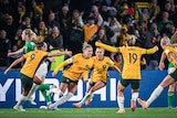 The Matildas celebrate by running towards each other near the goal.