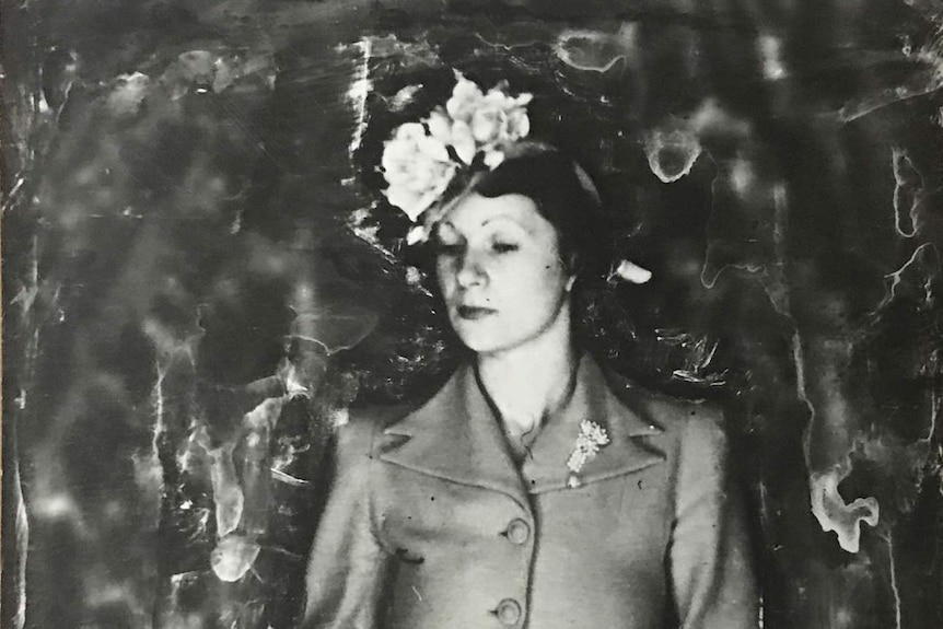 A black and white photo of a young woman in a hat, skirt and blazer.