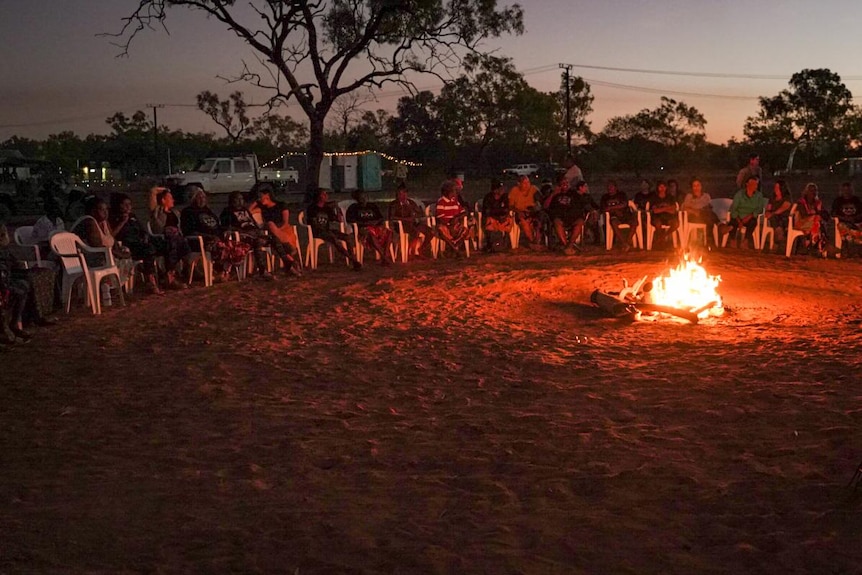 Women sit around a campfire.
