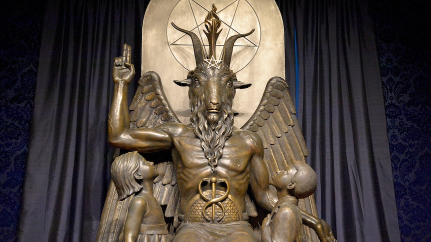 Imposing statue of Baphomet flanked by children with pentagram in the background