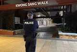 A police officer faces a walkway marked off with police tape