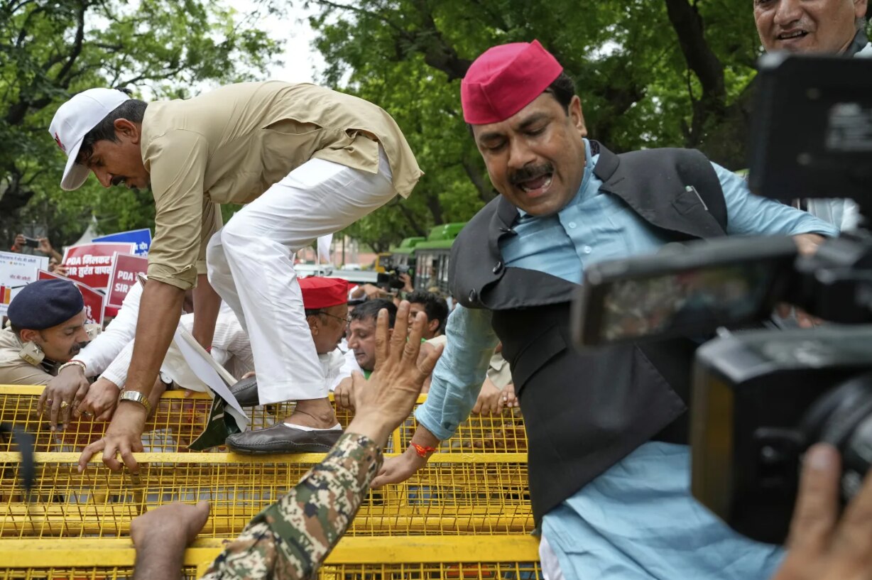 A crowd of protesters in India jumping over a barricade