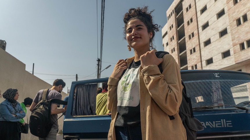 A young woman stands on the streets of Gaza