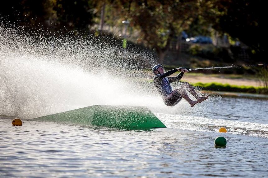 A barefoot skier launches over a jump on the River Torrens