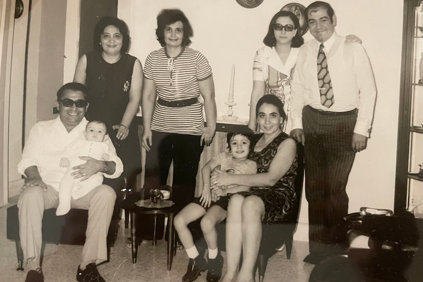 A black and white photo of a family. A young girl is cradled by her father.