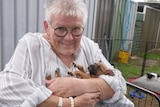 Cheryl cradling a small brown puppy asleep in her arms 