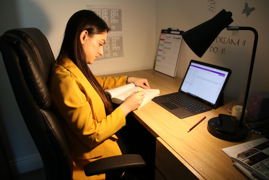 A woman sat at a desk reading a book