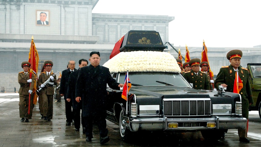 Kim Jong-Un walks besides the convoy carrying the body of his father