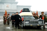 Kim Jong-Un walks besides the convoy carrying the body of his father