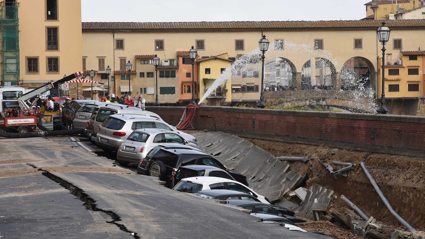 Cars are partially submerged in the embankment near the Ponte Vecchio bridge.