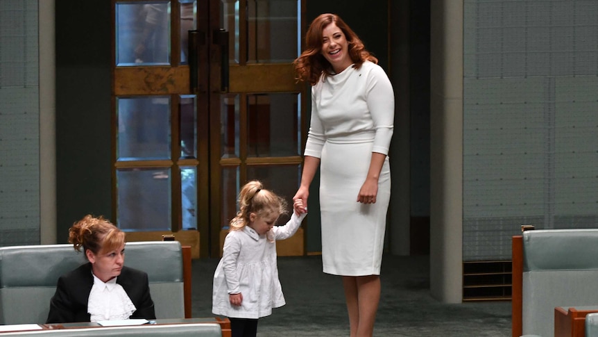 Anika Wells holds the hand of her young daughter on the floor of the House of Representatives.