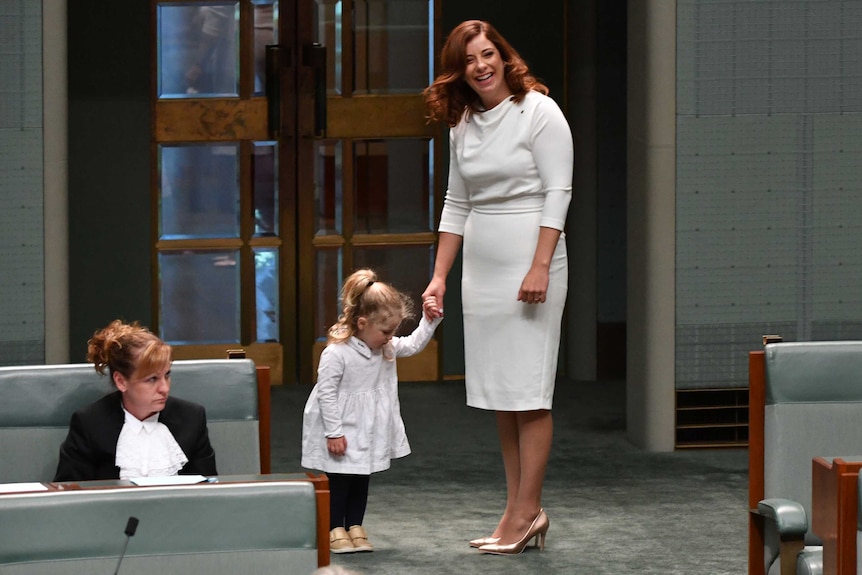 Anika Wells holds the hand of her young daughter on the floor of the House of Representatives.