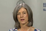 A woman with grey hair wearing a dress with a floral print