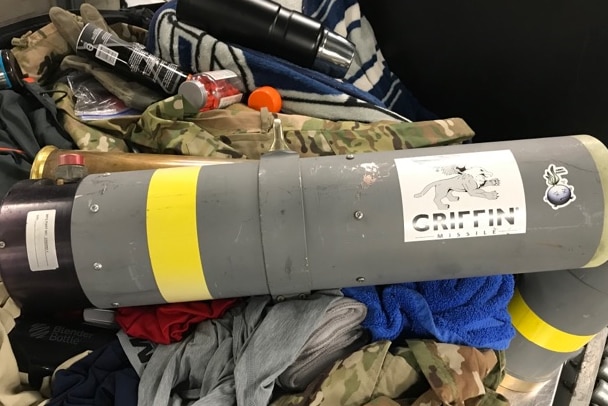 A missile launcher sits on top of a camouflage print bag