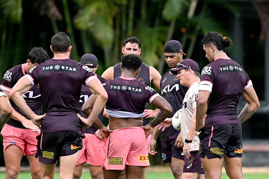 An NRL coach is surrounded by his players as he talks to them during training.