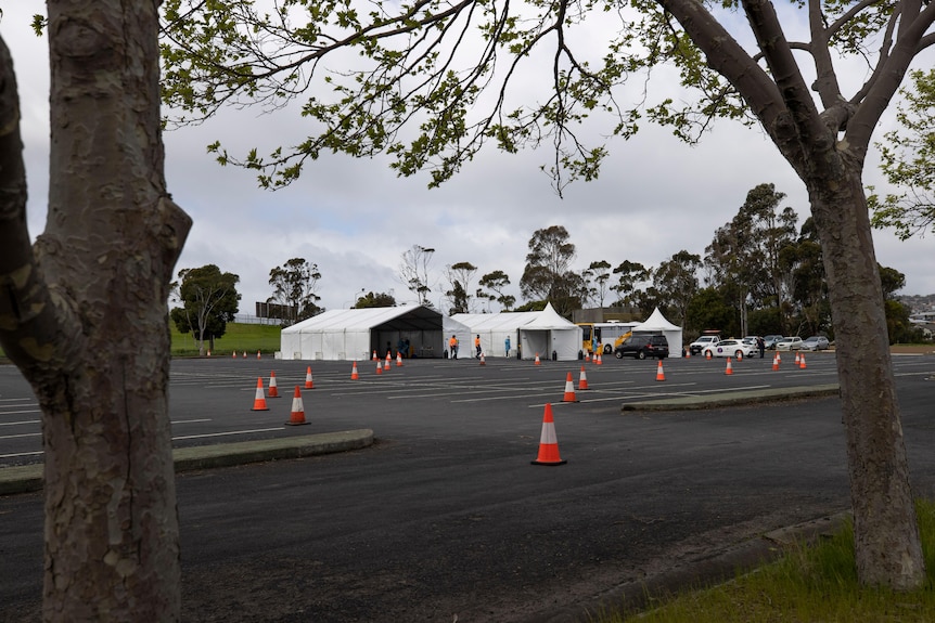 White tents in an empty carpark, with traffic cones in front
