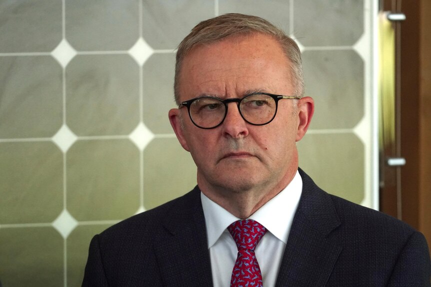Anthony Albanese wears a serious expression at a press conference