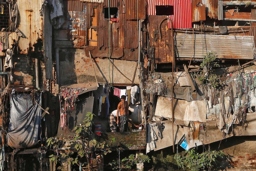 A man brushes his teeth outside a shanty