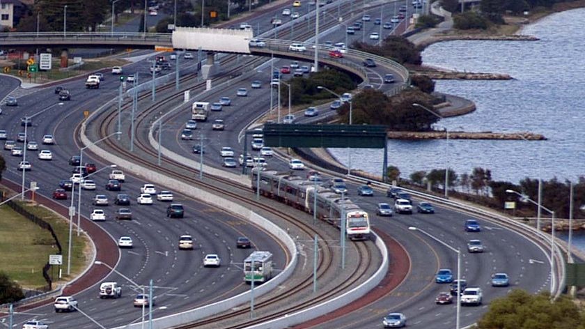 A train makes its way along the tracks located in the middle of the Kwinana Freeway