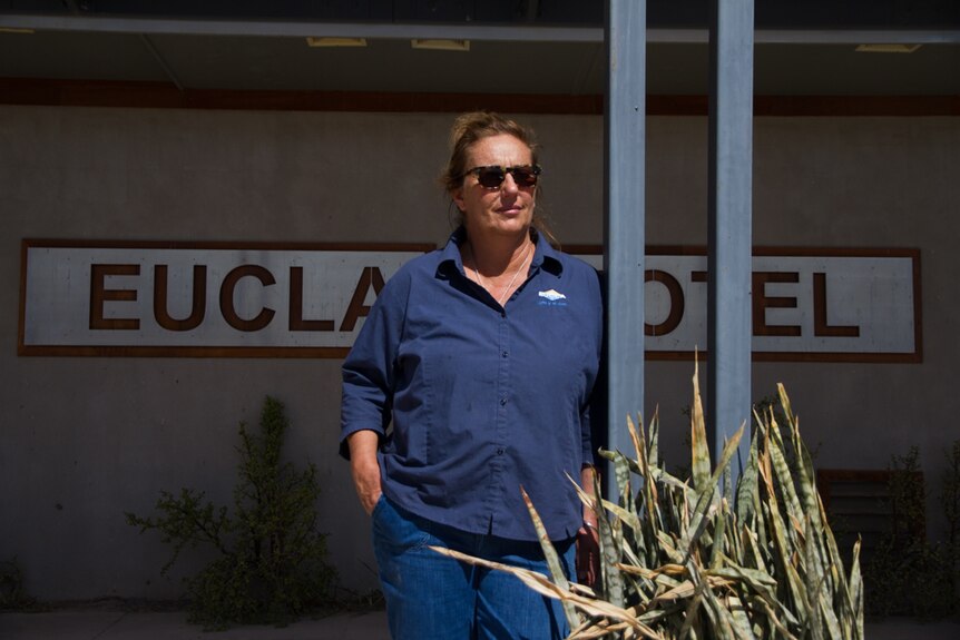 A woman pictured standing in front of a building, with a sign that reads 'Eucla Motel'