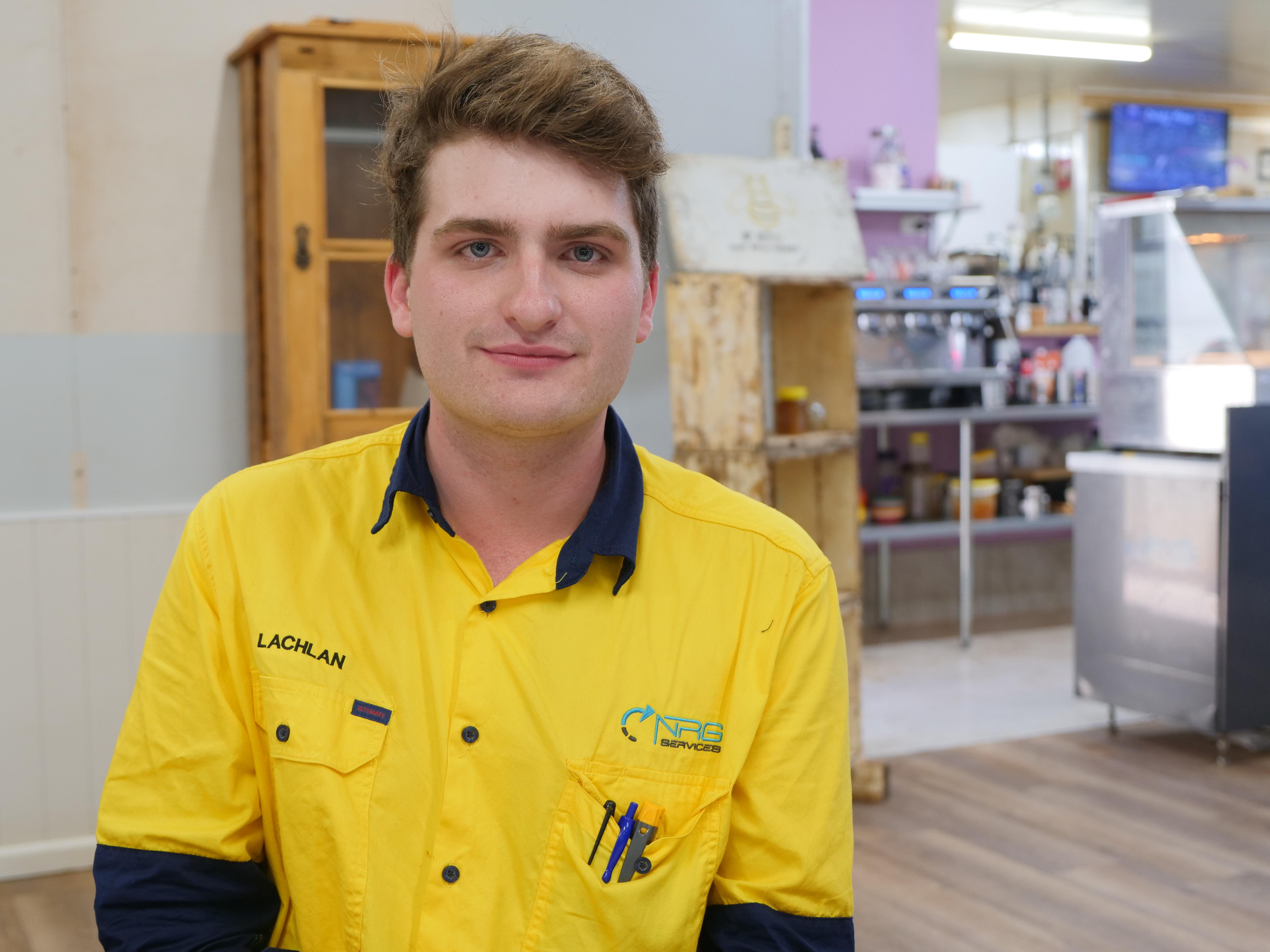 Um jovem com uma camiseta de negócios está sentado dentro de um posto de gasolina.