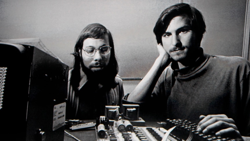 Apple Chief Executive Officer Steve Jobs stands beneath a photograph of him and Apple-co founder Steve Wozniak