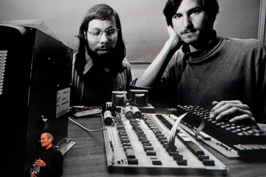 Apple Chief Executive Officer Steve Jobs stands beneath a photograph of him and Apple-co founder Steve Wozniak