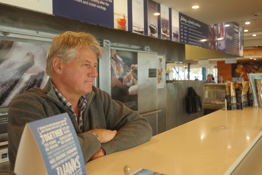 man leaning on counter in fish shop