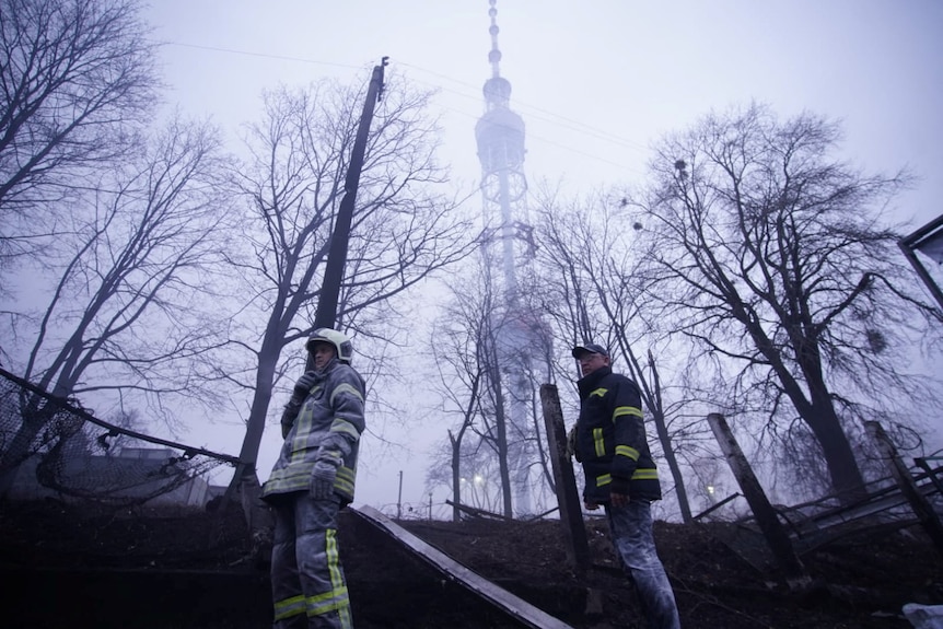Two emergency workers stand in a huge cloud of dust and debris under the Kyiv television tower.