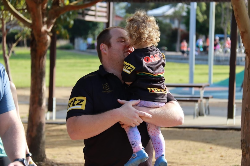 A father holds his toddler at The Ponds parkrun. 