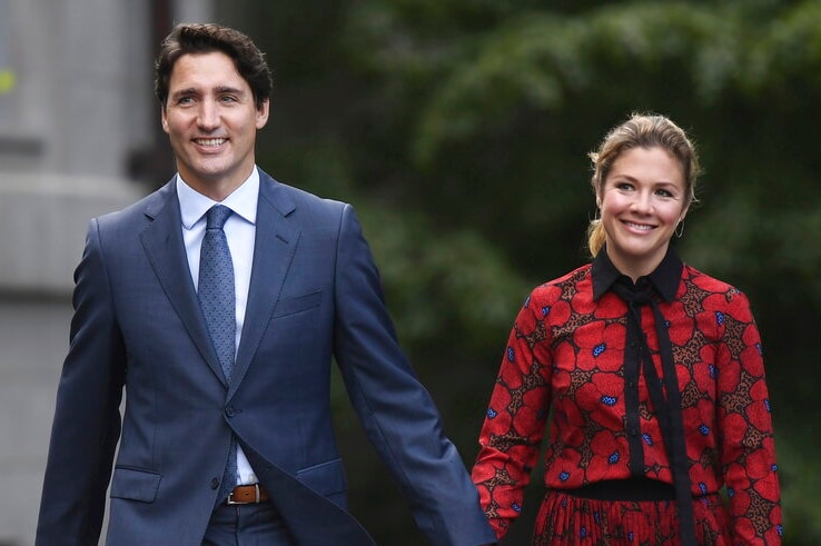 Justin Trudeau and his wife holding hands and smiling.