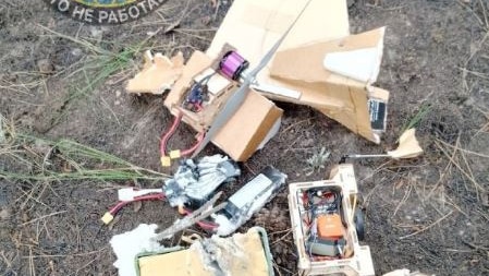 A smashed drone on the ground. The drone is made from cardboard and has electronics strewn across the ground