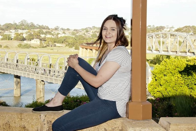Aninna Tarasenko sits with a river and bridge in the background.