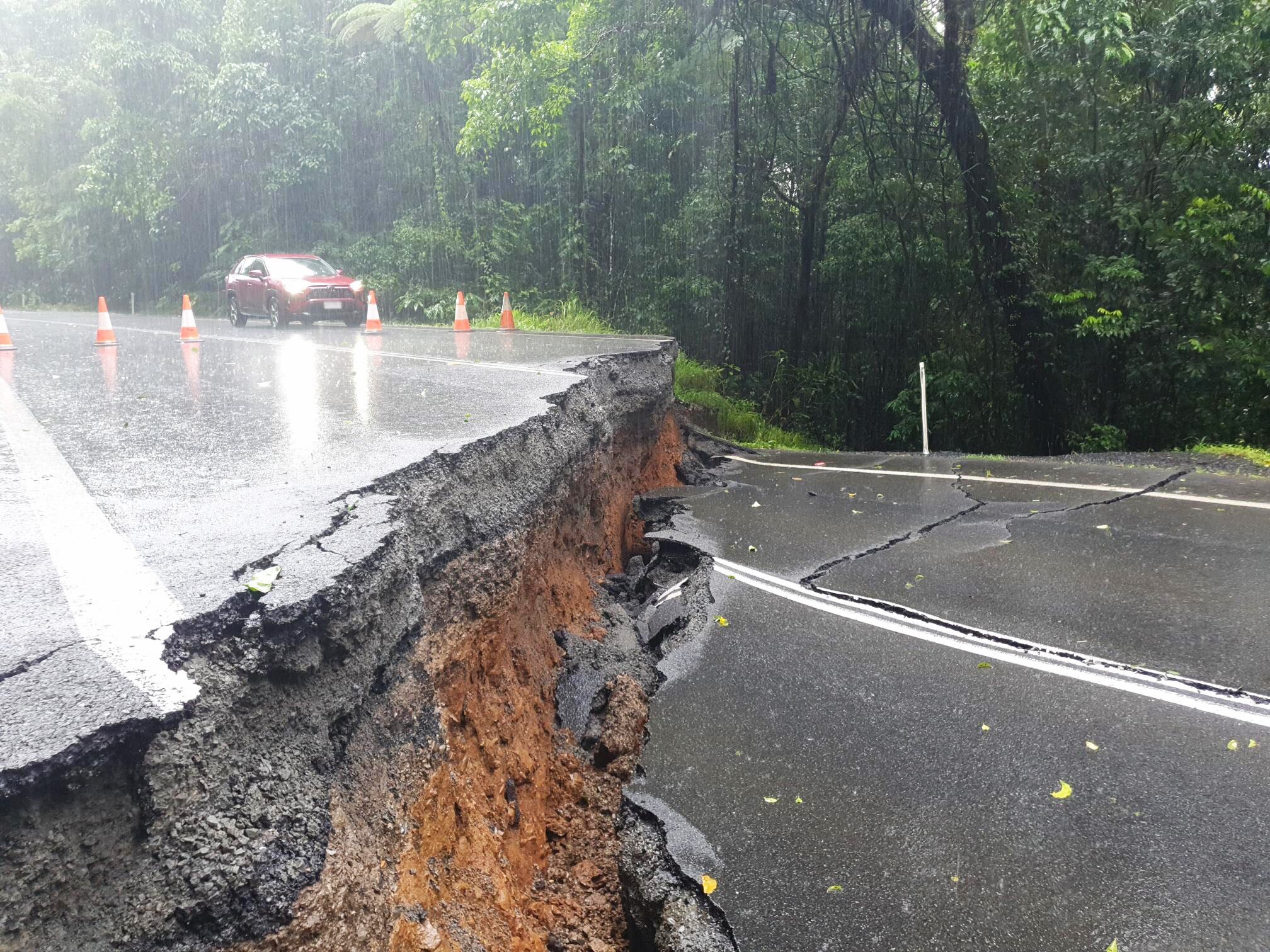 A massive crack in a bitumen road with vegetation behind it