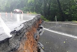 A massive crack in a bitumen road with vegetation behind it