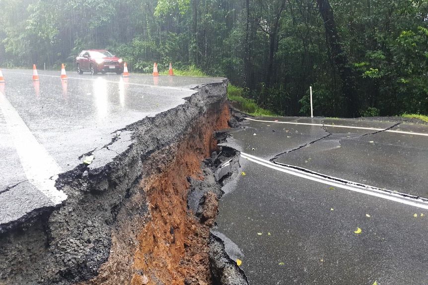 A massive crack in a bitumen road with vegetation behind it