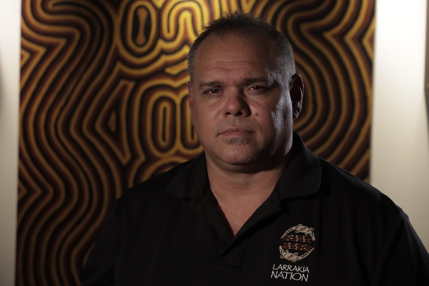 An Indigenous man looks at a camera in a dark room