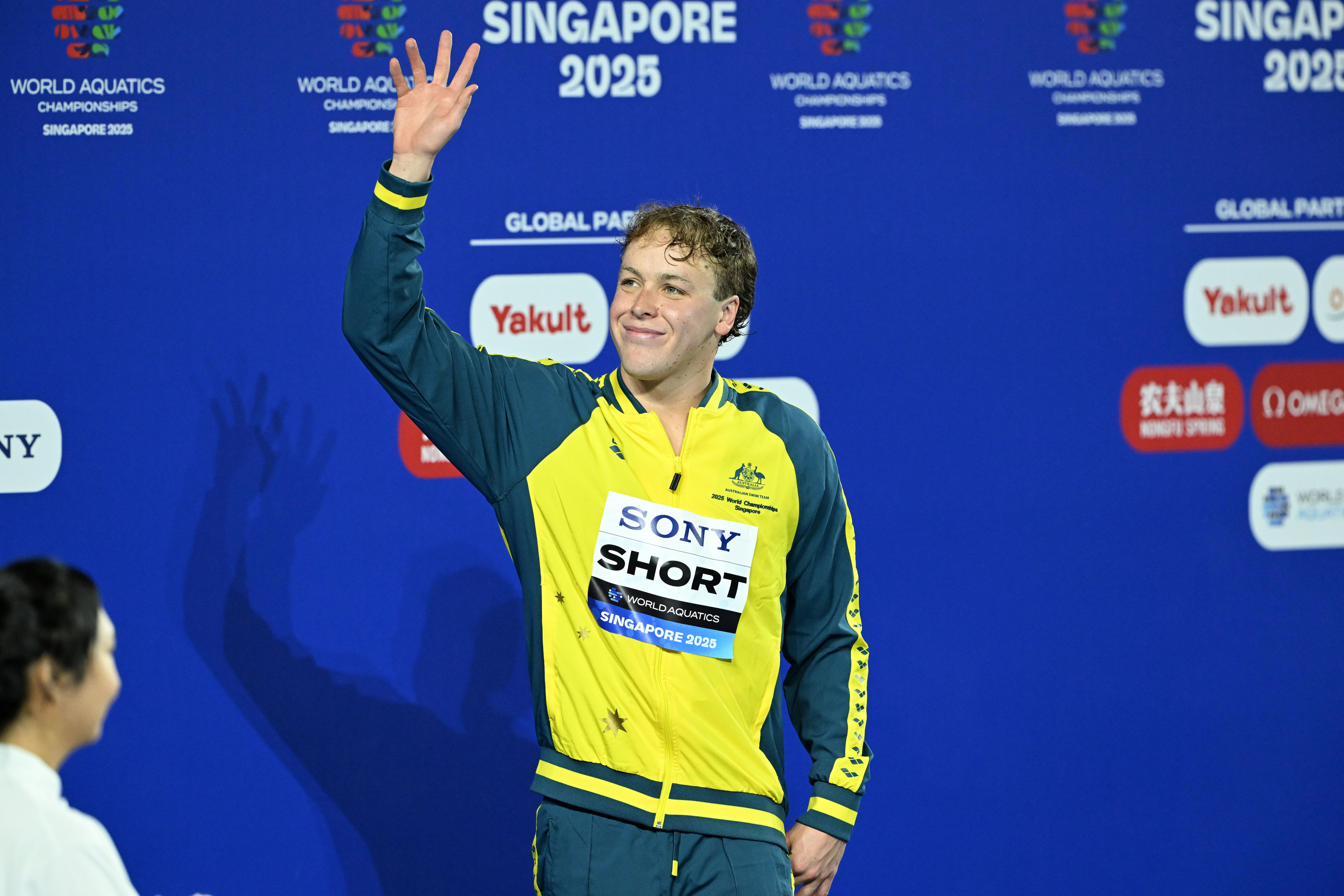 A young male swimmer in a green and gold tracksuit.
