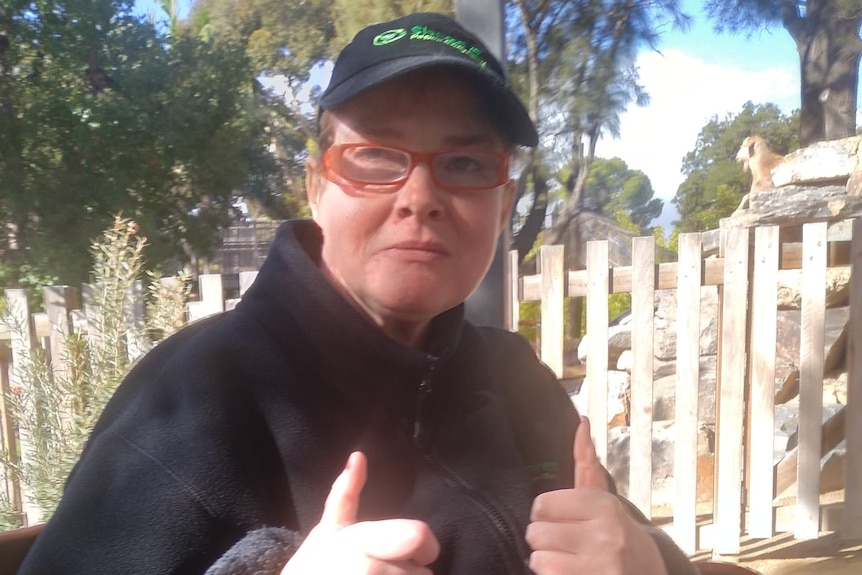 A woman wearing a hat and glasses sitting outdoors